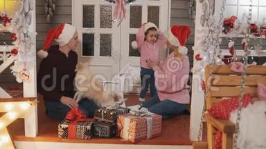 家人为圣诞节<strong>打包礼物</strong>。 带圣诞装饰的家庭在门廊微笑