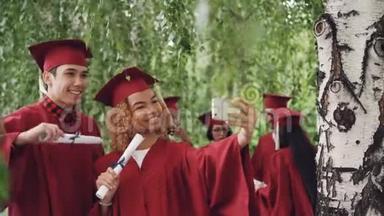 快乐的年轻人女孩和男孩在毕业典礼后自拍，他们穿着长袍和文凭
