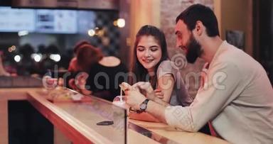有魅力的年轻夫妇晚上晚些时候在咖啡馆里使用智能<strong>手机</strong>。 朋友，交流，情侣，<strong>约会</strong>，聊天