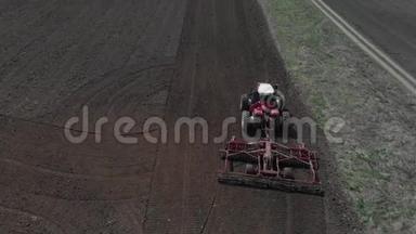 拖拉机在播种季节开始时在地上犁地。一个农民站在他的铁轨上