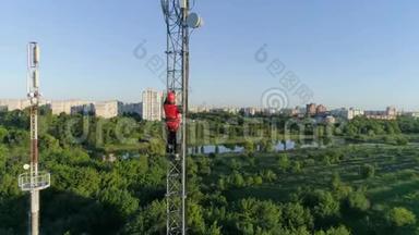 戴着安全帽的工人在无线电塔上高攀，背景是美丽的城市景观，鸟瞰。