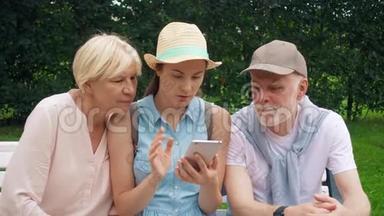 老人和女儿坐在公园里用<strong>手机浏览</strong>。 家庭在网上寻找方向