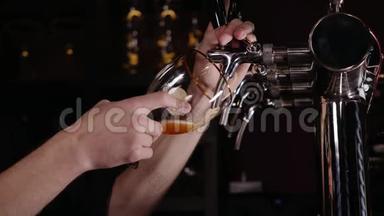 酒保在餐馆或酒吧的水龙头里倒一大杯啤酒的手。