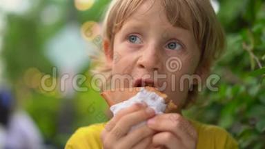 一个小男孩在街头市场吃美味的煎饼的特写镜头。 街头美食概念。