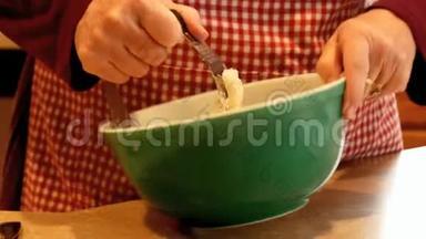 女人用手在绿色的碗里搅拌饼<strong>干面</strong>团。