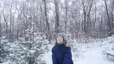 少年男孩在冬天的森林里扔雪。 积极的生活方式，冬季活动，户外冬季游戏的概念