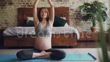 美丽的准妈妈正在现代公寓里练习哈他瑜伽，坐在<strong>垫子</strong>上，穿着孕妇运动服