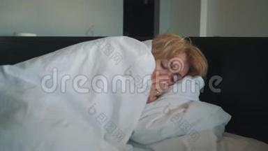 一个感冒的女人，感觉不好，吹进鼻子里，裹着一条白色的毯子。 医生`医疗帮助