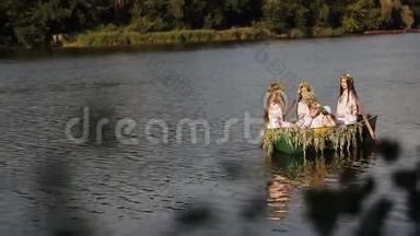 <strong>三个</strong>漂亮的<strong>女孩</strong>穿着斯拉夫的衣服坐在河上的一艘船上。 女人互相传递一束野花。 <strong>女孩</strong>