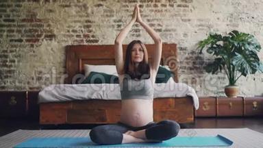 多莉拍了一张漂亮的期待妈妈在家练习瑜伽的照片，坐在卧室地板上的<strong>垫子</strong>上，摆出莲花的姿势，举起了瑜伽