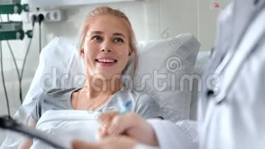 男医生在<strong>病床</strong>上与女病人交谈。 带剪贴板和x光照片的微笑医生
