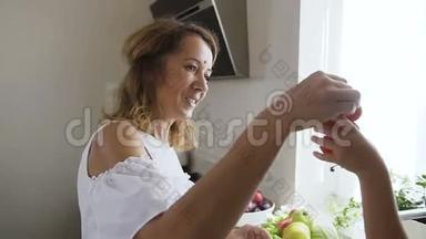 年轻的女人和穿着白色衣服的女孩吃着美味的红西红柿，在
