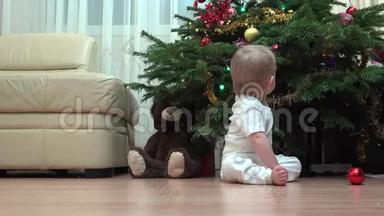 有趣的宝宝坐在圣诞树下玩装饰，孩子爬