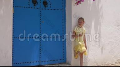 带着冰淇淋的少女在白色的背景墙上摆着蓝色的门