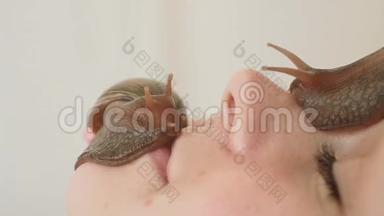 两只大蜗牛在脸上。 在水疗中心的年轻女子接受了一个与蜗牛Achatina的面部按摩。 蜗牛吃死皮