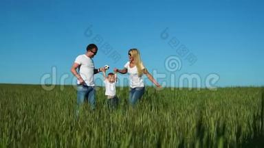 幸福的家庭：<strong>爸爸妈妈</strong>和儿子穿着白色的t恤衫和牛仔裤在田野里跳着笑