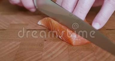 寿司主厨拿起一把刀，用一把锋利的刀切下日本生鱼片和寿司用的脂肪肚三文鱼薄片。