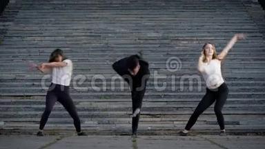 <strong>当代舞者</strong>在户外表演，两个女孩和一个男人在广场上跳舞。