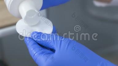 美容师`双手戴蓝色橡胶手套，把清洁剂放在棉垫上进行治疗。 双手特写..