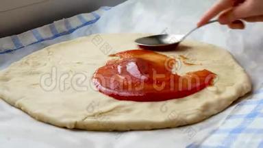 厨师用勺子在披萨面团上撒番茄酱