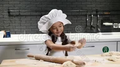 戴着厨师帽和围裙的漂亮女孩。 小厨师的概念。 可爱的女孩玩面团。 4k