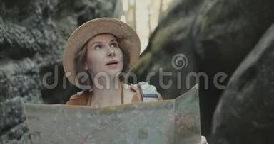 年轻快乐的女人旅行和寻找地标，女孩带地图在岩石中心
