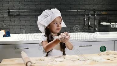 小<strong>厨师</strong>的概念。 穿着<strong>厨师</strong>帽和<strong>厨师</strong>围裙用面团做饭的漂亮小女孩。 年轻的炊具持有滚针。 4k