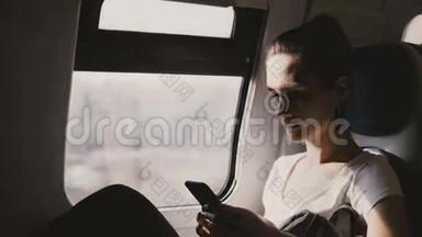 年轻漂亮的高加索女人坐在火车的靠窗的座位上，在上班的路上用智能<strong>手机</strong>在应用程序上<strong>输入</strong>信息