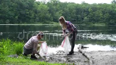 志愿者在河边<strong>清理垃圾</strong>.. 女人在湖里捡起一瓶塑料。 环境污染