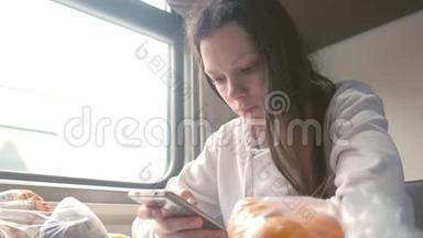 疲惫的女人正在智能手机上读一本书，坐长途火车旅行。