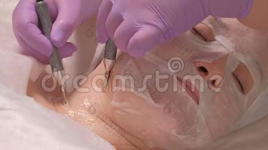 微<strong>电流</strong>。 一位戴紫丁香手套的专业美容师在两个电极的帮助下，抚平女孩脖子上的皱纹。