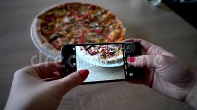 餐馆里的年轻女子用<strong>手机</strong>相机<strong>制作</strong>食物照片。 女人拍披萨的照片