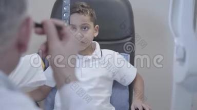 英俊的穆拉托男孩坐在医生的椅子上的肖像。 专业<strong>眼科</strong>医生检查