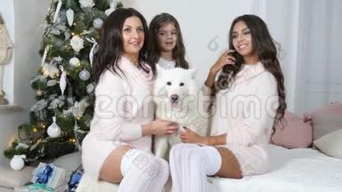 圣诞节一家人，母亲带着女儿和狗坐在沙发上，在镜头前拍照