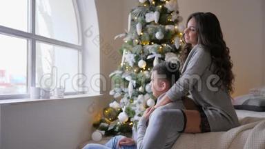 庆祝气氛，女孩坐在沙发上拥抱她的男朋友，看着窗外靠近圣诞树