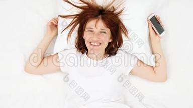 微笑少年女孩在床上用手机拍照。 顶部视图