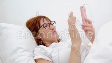 病人在床上用手机说话。 病床上年轻迷人的女人。 连接世界和移动办公