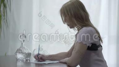 肖像，美丽的，苗条的，金发的女人，穿着骨科胸衣，坐在桌子上写着一封信