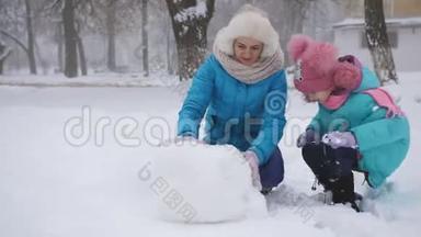母女俩在雪地里滚了一个大球，<strong>堆雪人</strong>。