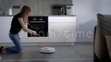 布鲁内特女孩在厨房里玩<strong>吸尘</strong>器机器人，<strong>吸尘</strong>地板。