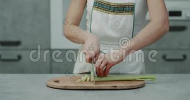 厨房衣柜里的女人用一把大刀切了一根大芹菜，用专业刀切。