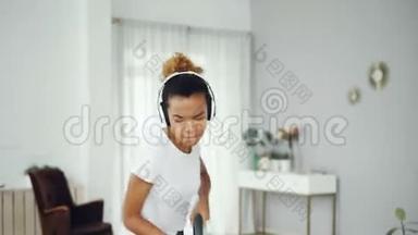 活跃的女家庭主妇正在<strong>用</strong>吸尘器打扫房间，<strong>用</strong>耳机听音乐，跳舞和