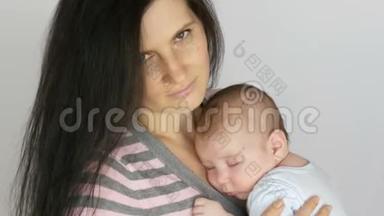 年轻美丽的黑发长发母亲，两个月大的新生儿睡在她的<strong>怀里</strong>。 <strong>妈妈</strong>抱着她