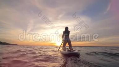 日落时分，一位苗条的女士在划板游泳