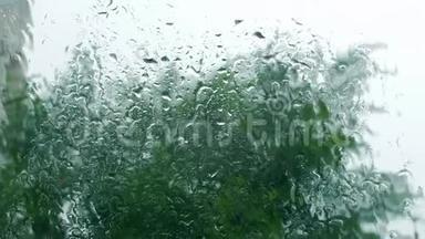 雨滴落在窗户玻璃上，建筑物在背景上。 从窗户看房子，暴风雨天气，强烈