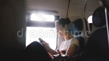美丽的欧洲<strong>女孩</strong>开心地笑着，使用智能手机<strong>社交网络</strong>应用程序，在火车窗口座位上环顾四周。