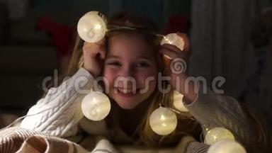 一个有圣诞灯的可爱女孩的肖像。 孩子躺在<strong>地板</strong>上玩圣诞花环，很有<strong>创意</strong>
