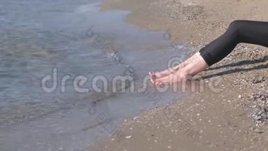 女人在沙滩上`<strong>脚踩</strong>着大海。 侧视。