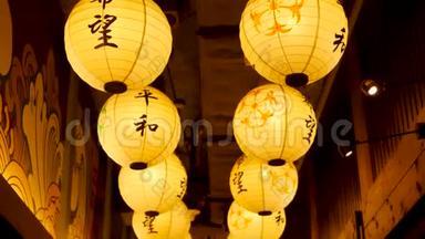 纸灯笼在街上闪闪发光。 美丽的纸灯笼在日本街道的狭窄通道上闪闪发光