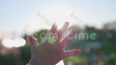 一个小朋友`笔向太阳招手.. 光线穿过你的手指。 欢迎来到太阳